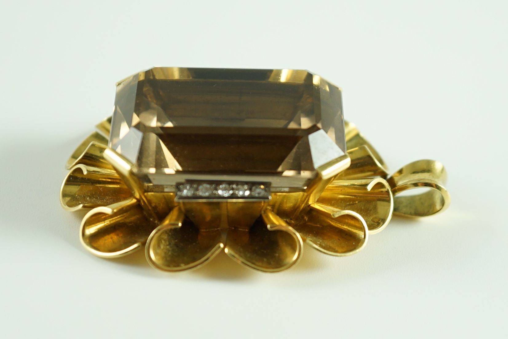 A modern 750 gold, emerald cut smoky quartz and diamond chip set oval pendant